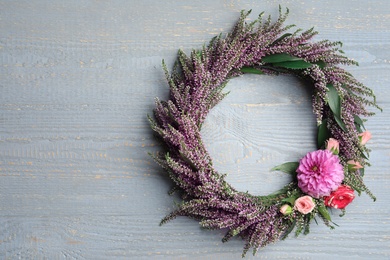 Beautiful autumnal wreath with heather flowers on light grey wooden background, top view. Space for text