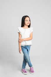 Photo of Cute little girl posing on light grey background