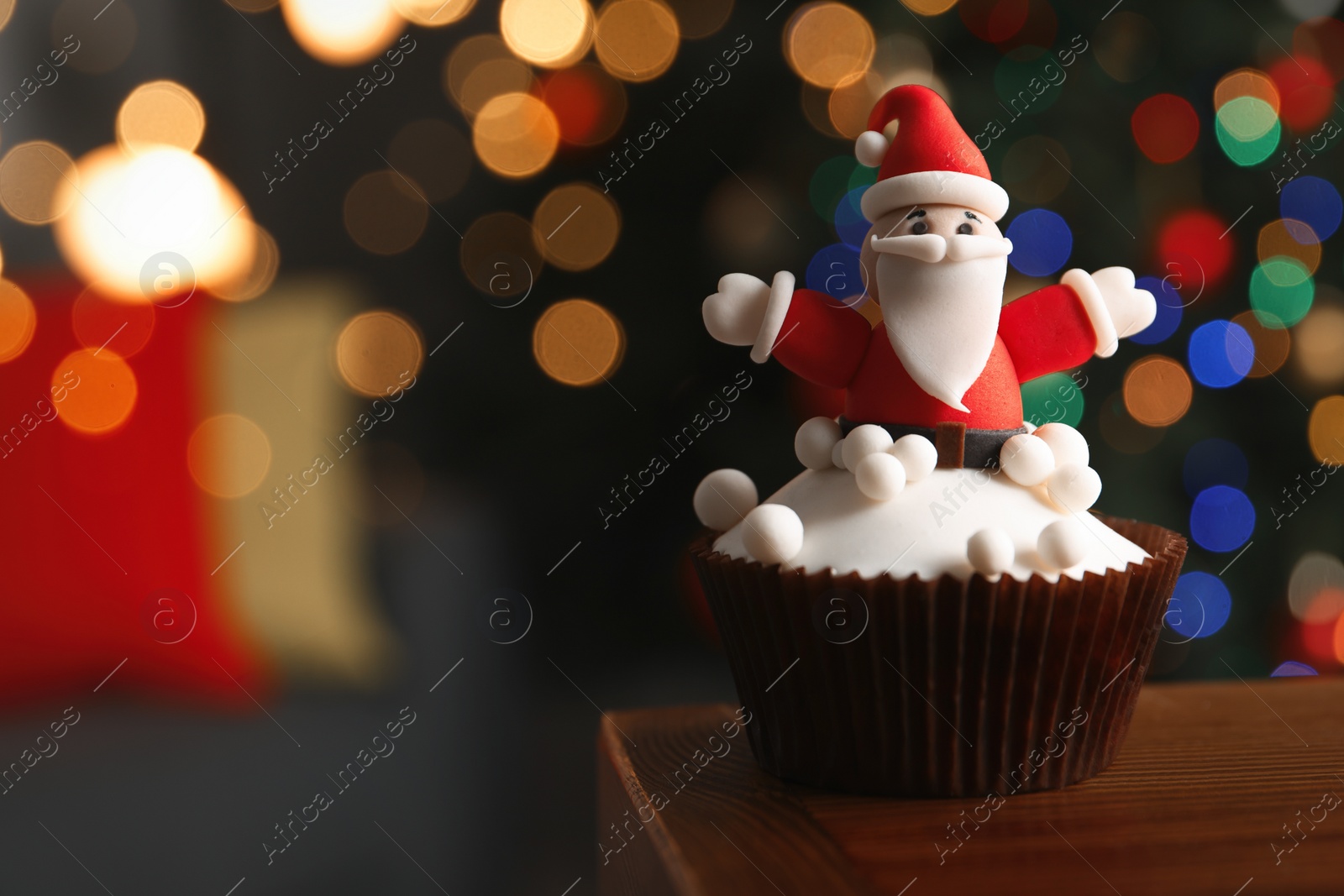 Photo of Beautifully decorated Christmas cupcake on wooden table indoors, closeup. Space for text