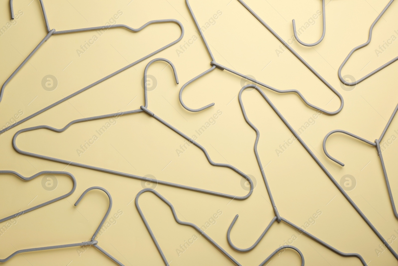 Photo of Hangers on pale yellow background, flat lay