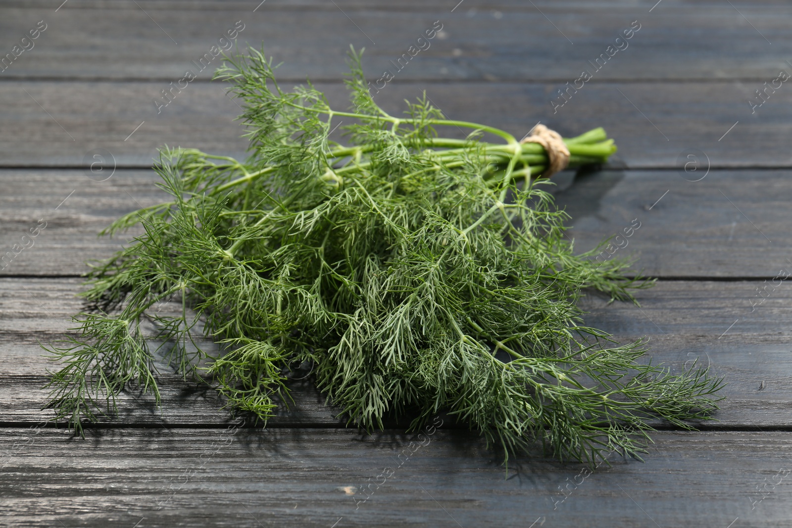 Photo of Bunch of fresh green dill on grey wooden table, closeup