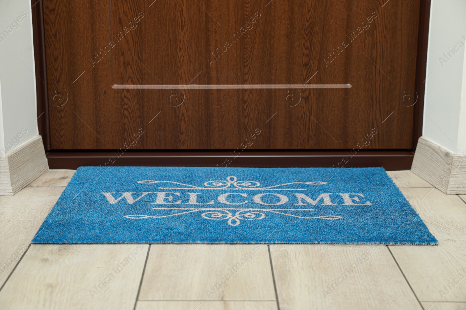 Photo of Beautiful blue doormat with word Welcome on floor near entrance