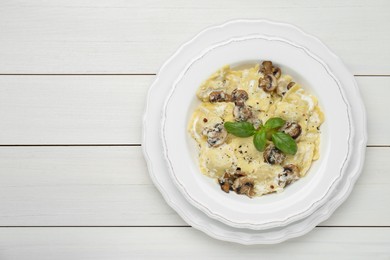Photo of Delicious ravioli with mushrooms and cheese on white wooden table, top view. Space for text