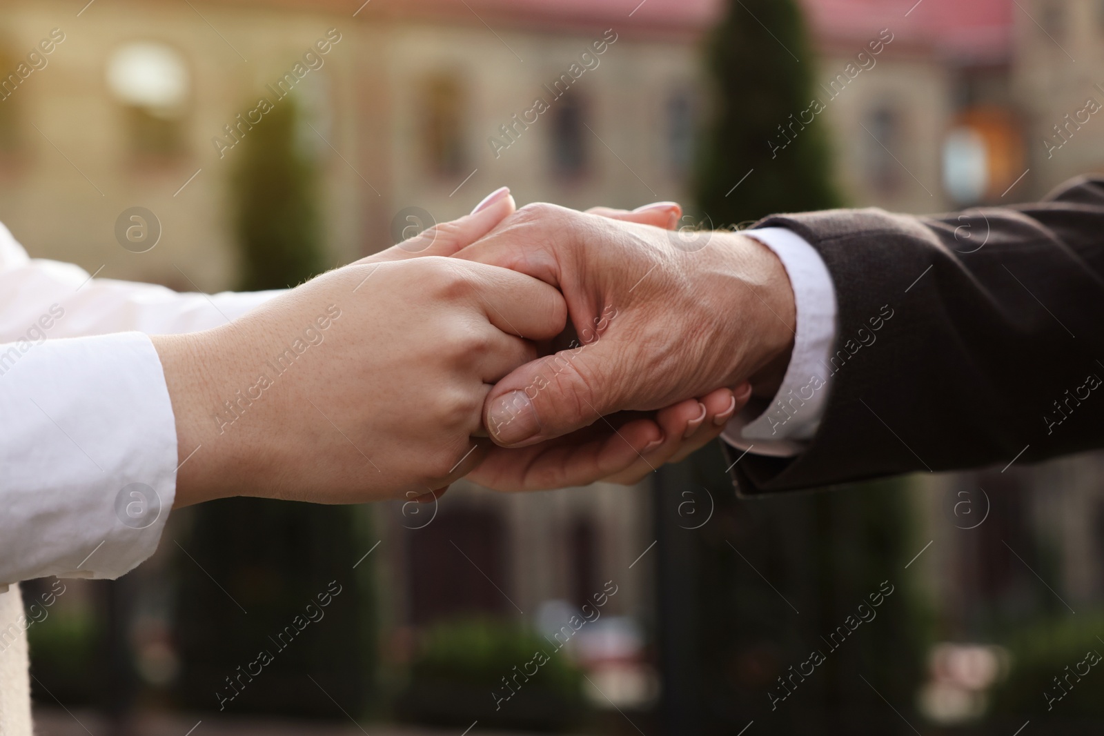 Photo of Trust and deal. Partners joining hands outdoors, closeup