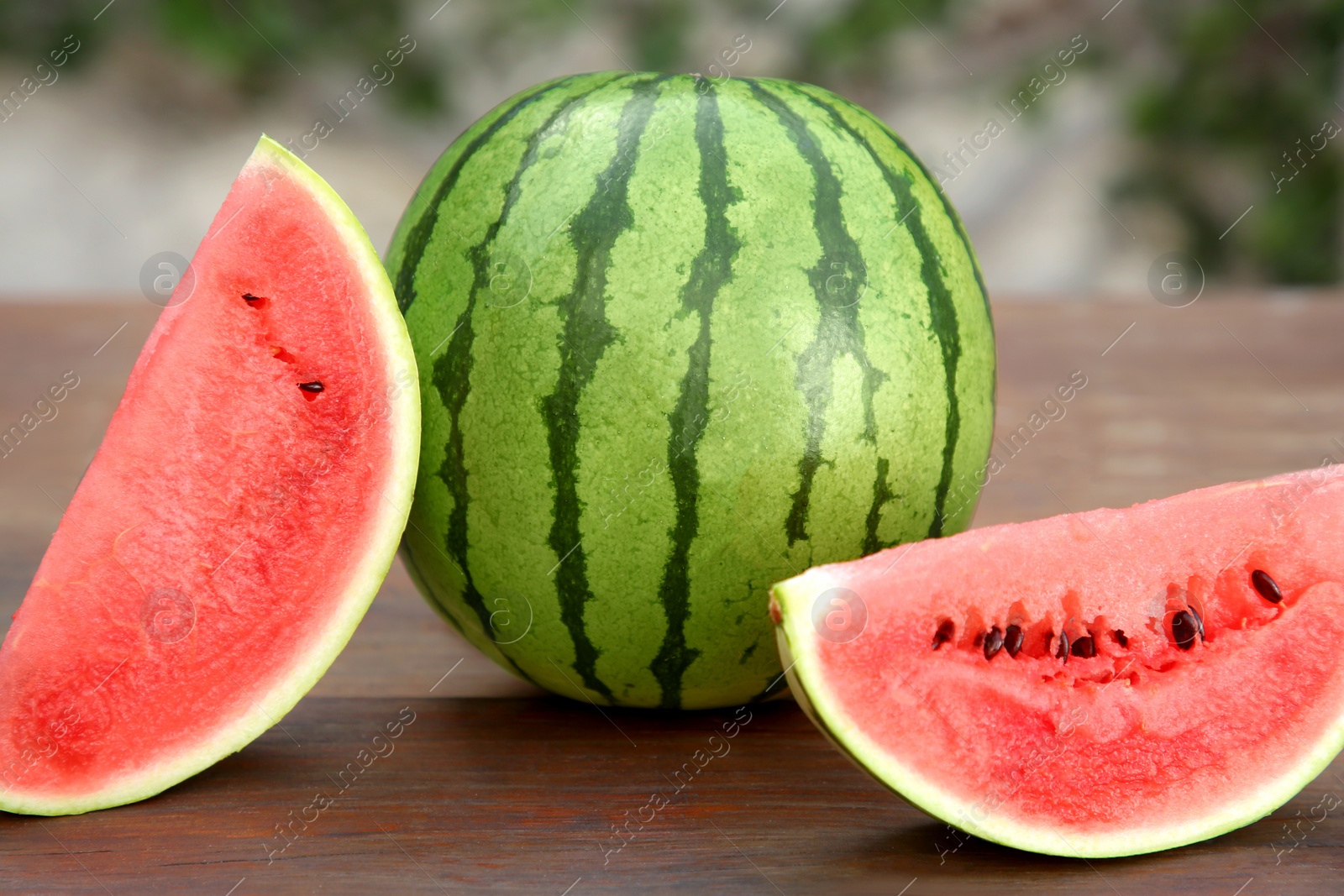 Photo of Delicious whole and cut watermelons on wooden table