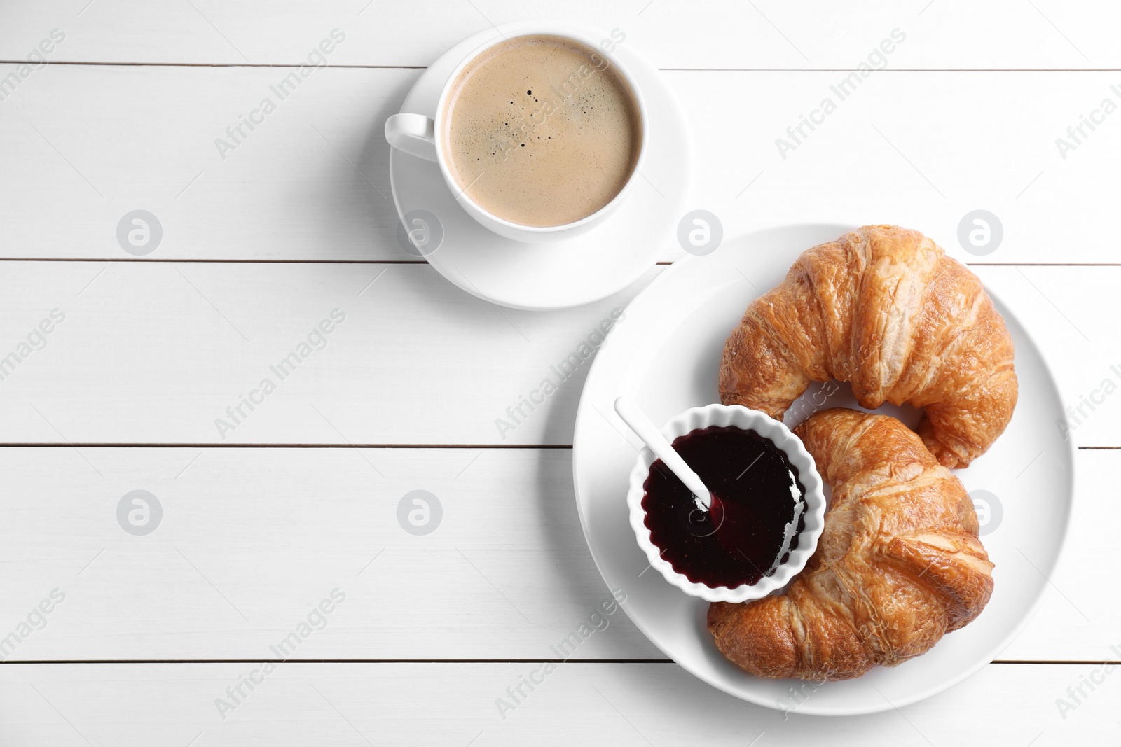 Photo of Breakfast time. Fresh croissants, jam and coffee on white wooden table, flat lay. Space for text