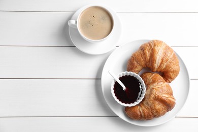 Photo of Breakfast time. Fresh croissants, jam and coffee on white wooden table, flat lay. Space for text