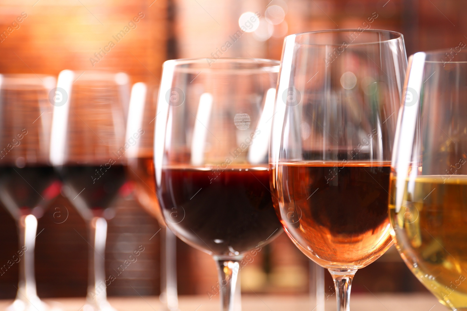 Photo of Different tasty wines in glasses against blurred background