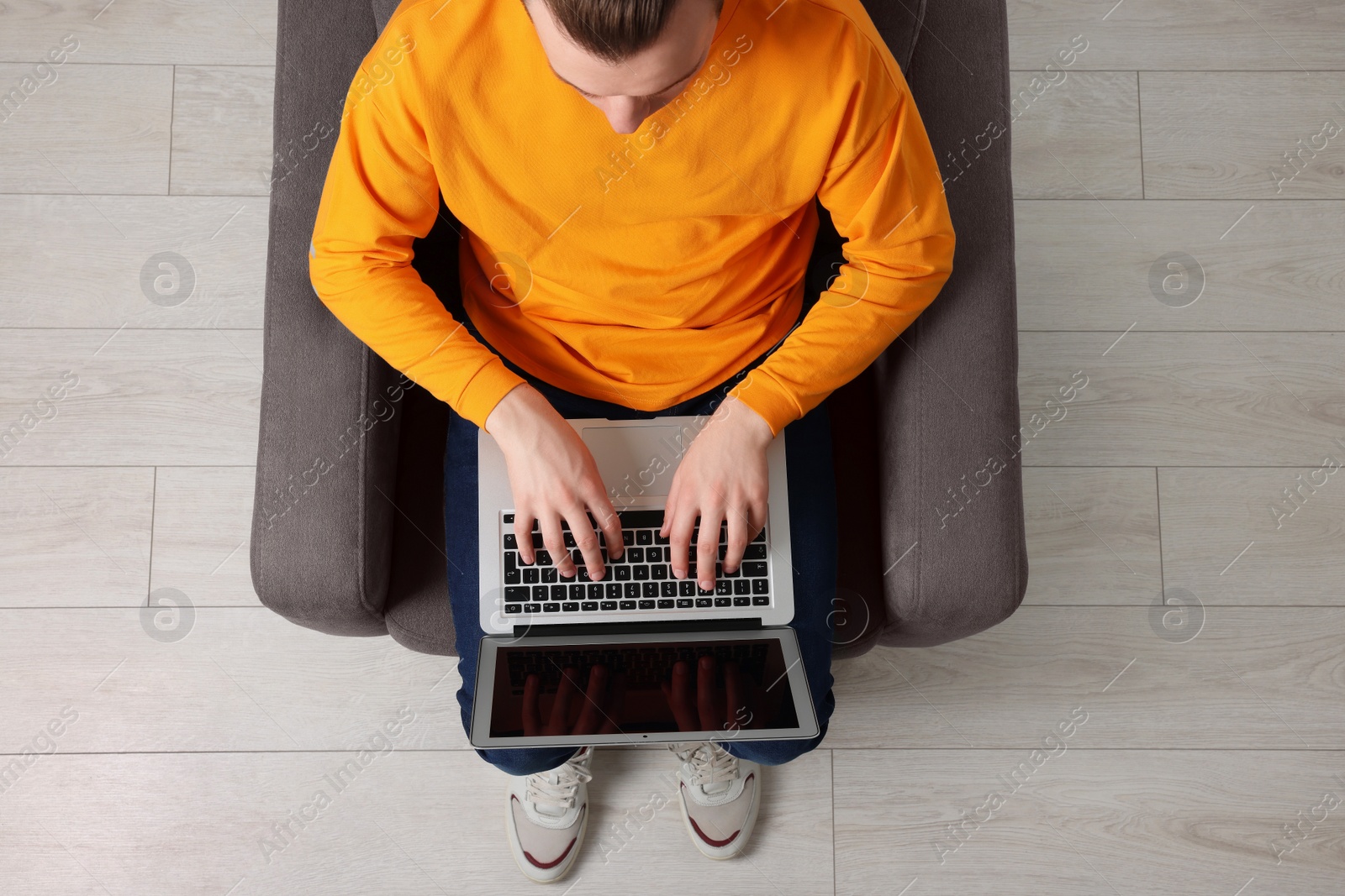 Photo of Man working with laptop in armchair, top view