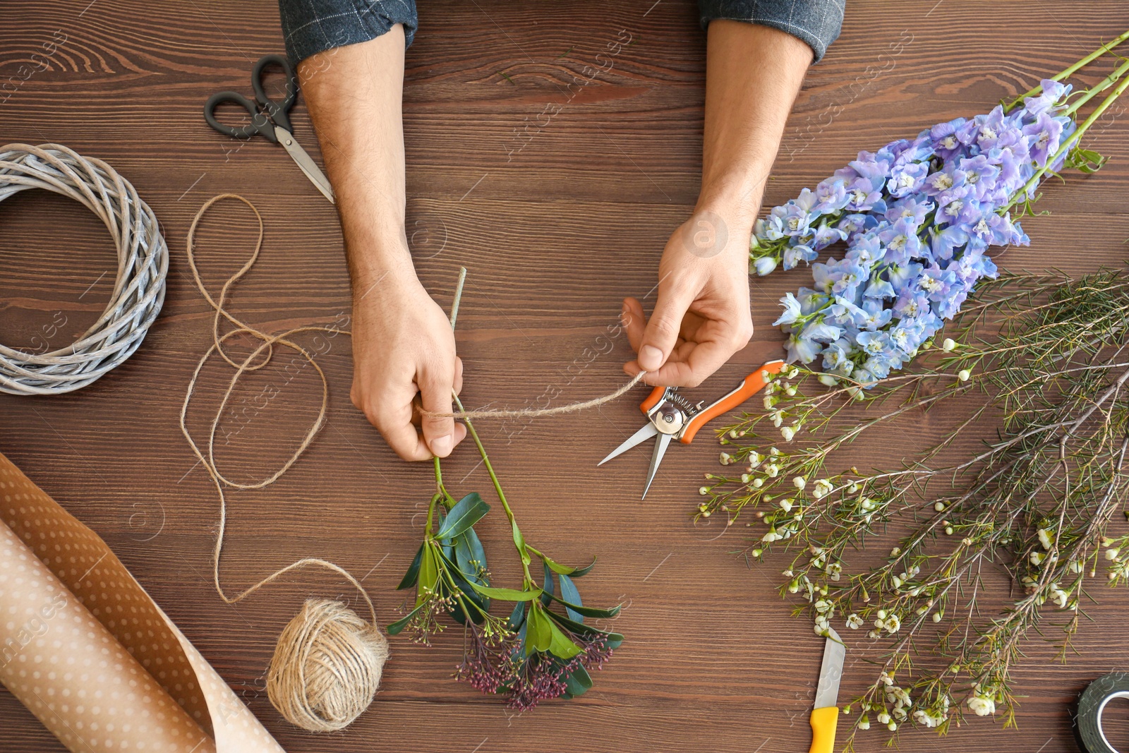 Photo of Male florist creating beautiful bouquet at table, closeup