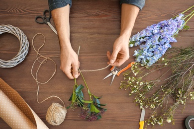 Male florist creating beautiful bouquet at table, closeup