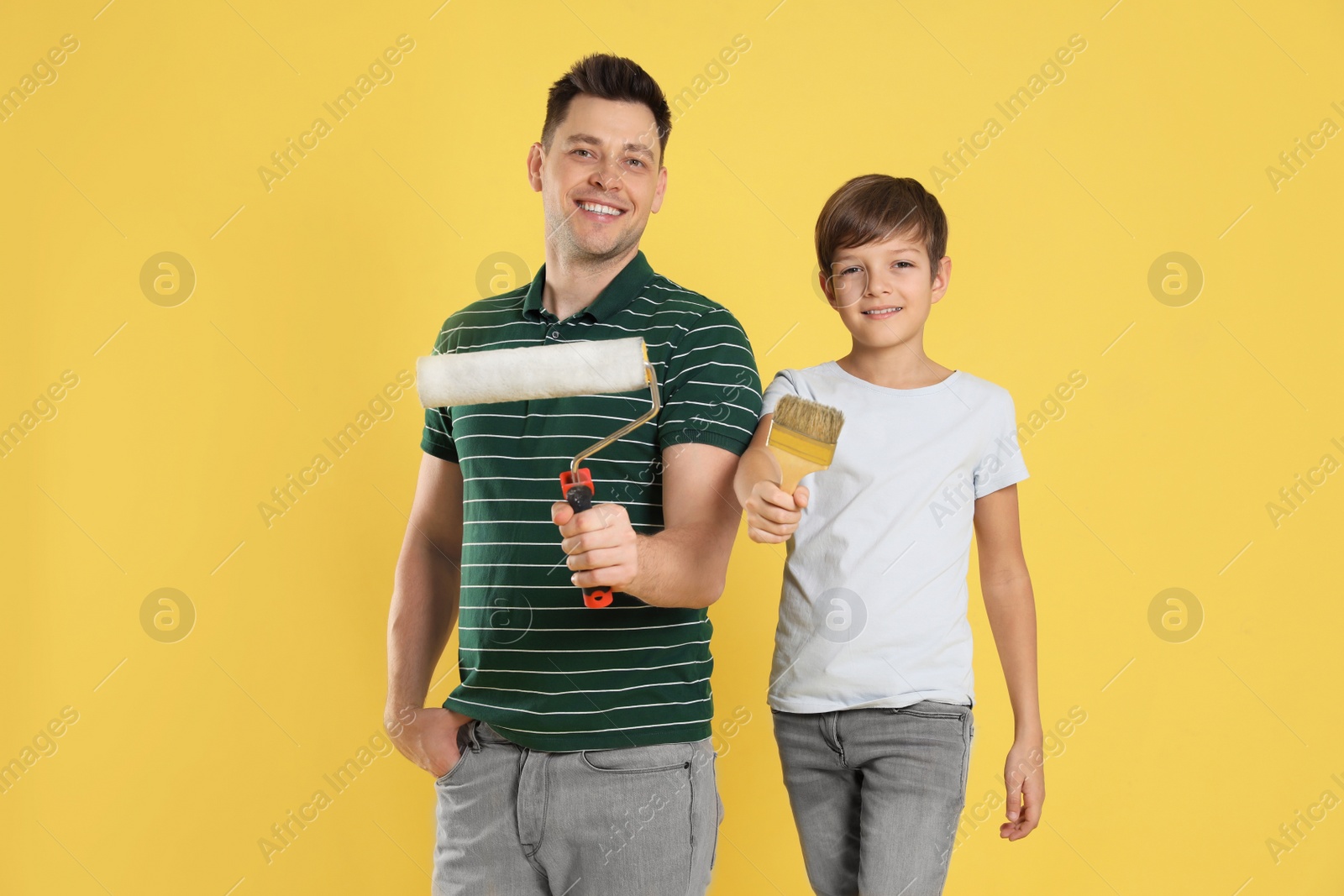 Photo of Dad and his son with painting tools on color background