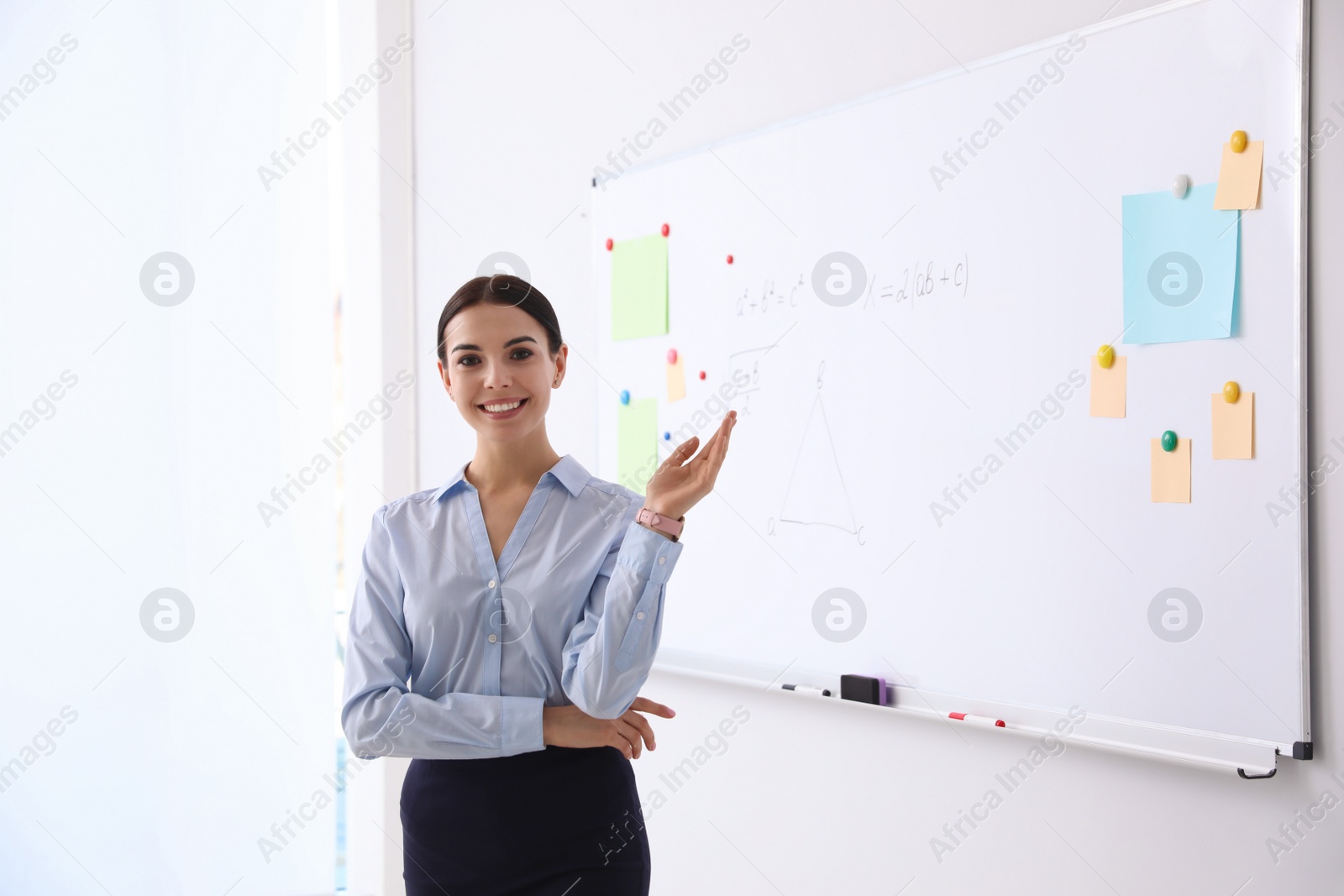 Photo of Young teacher near whiteboard in modern classroom