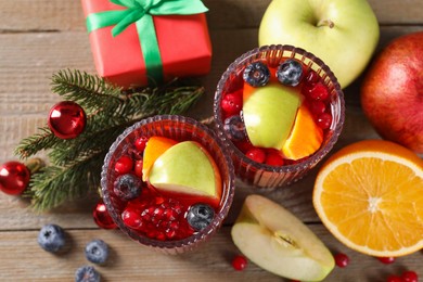 Photo of Aromatic Sangria drink in glasses, ingredients and Christmas decor on wooden table, flat lay