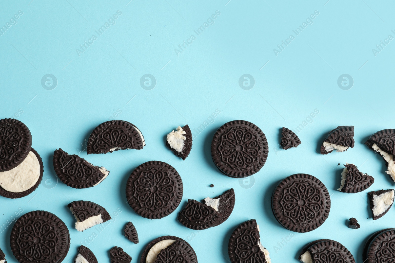 Photo of Tasty chocolate cookies with cream on color background, flat lay. Space for text