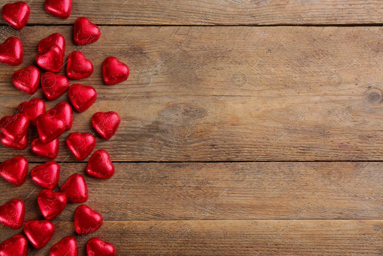 Photo of Heart shaped chocolate candies on wooden table, flat lay. Space for text