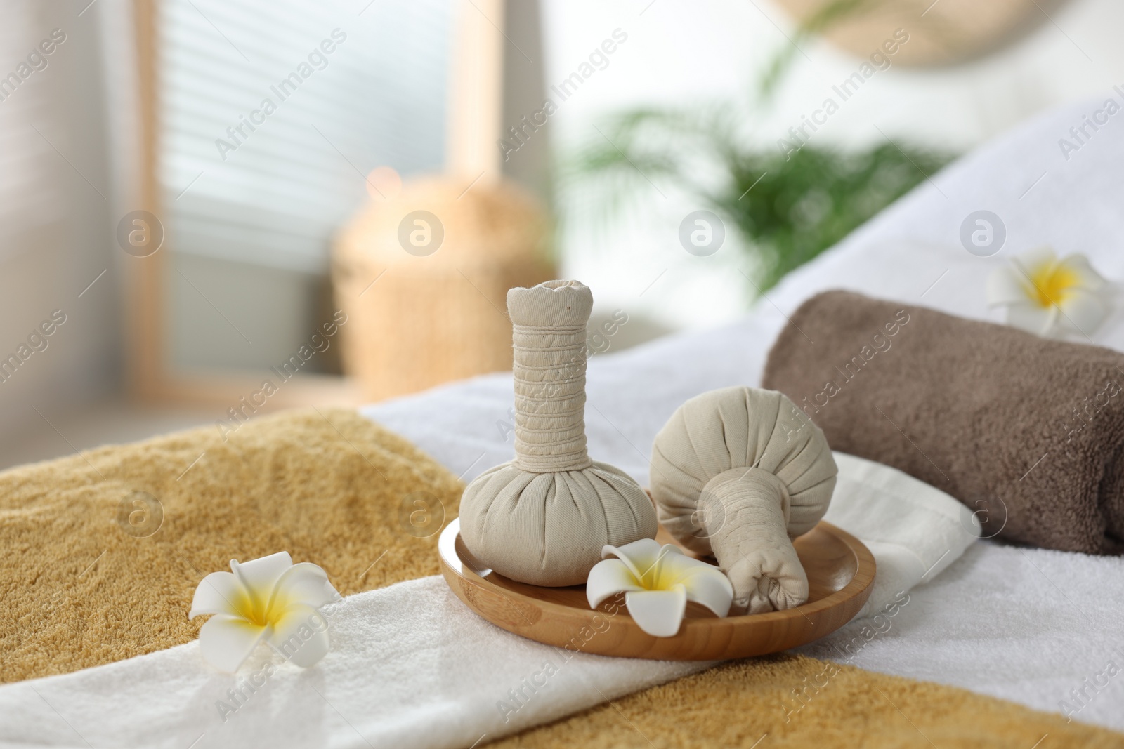 Photo of Herbal bags, flowers and towels on massage table in spa