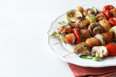 Delicious shish kebabs with vegetables and microgreens on white table, closeup. Space for text