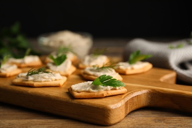 Photo of Delicious crackers with humus, parsley and dill on wooden table, closeup