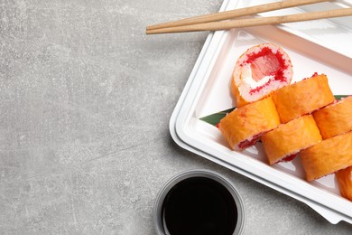 Photo of Food delivery. Delicious sushi rolls served on light grey table, flat lay with space for text