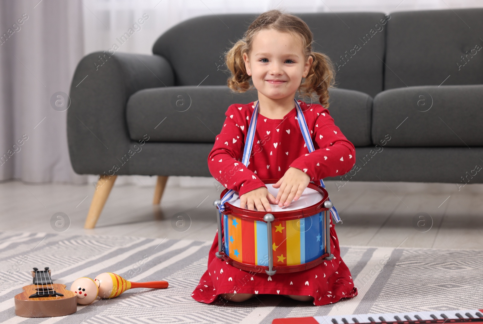 Photo of Little girl playing toy drum at home