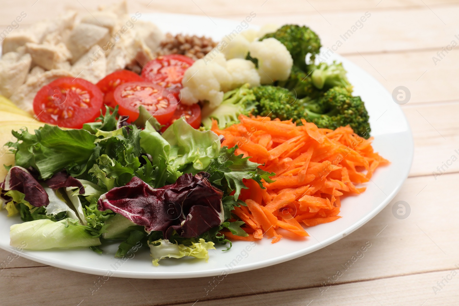 Photo of Balanced diet and healthy foods. Plate with different delicious products on light wooden table, closeup