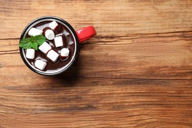 Photo of Mug of delicious hot chocolate with marshmallows and fresh mint on wooden table, top view. Space for text