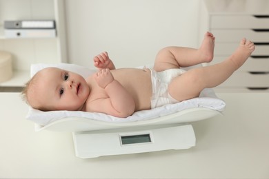 Cute little baby lying on scales in clinic