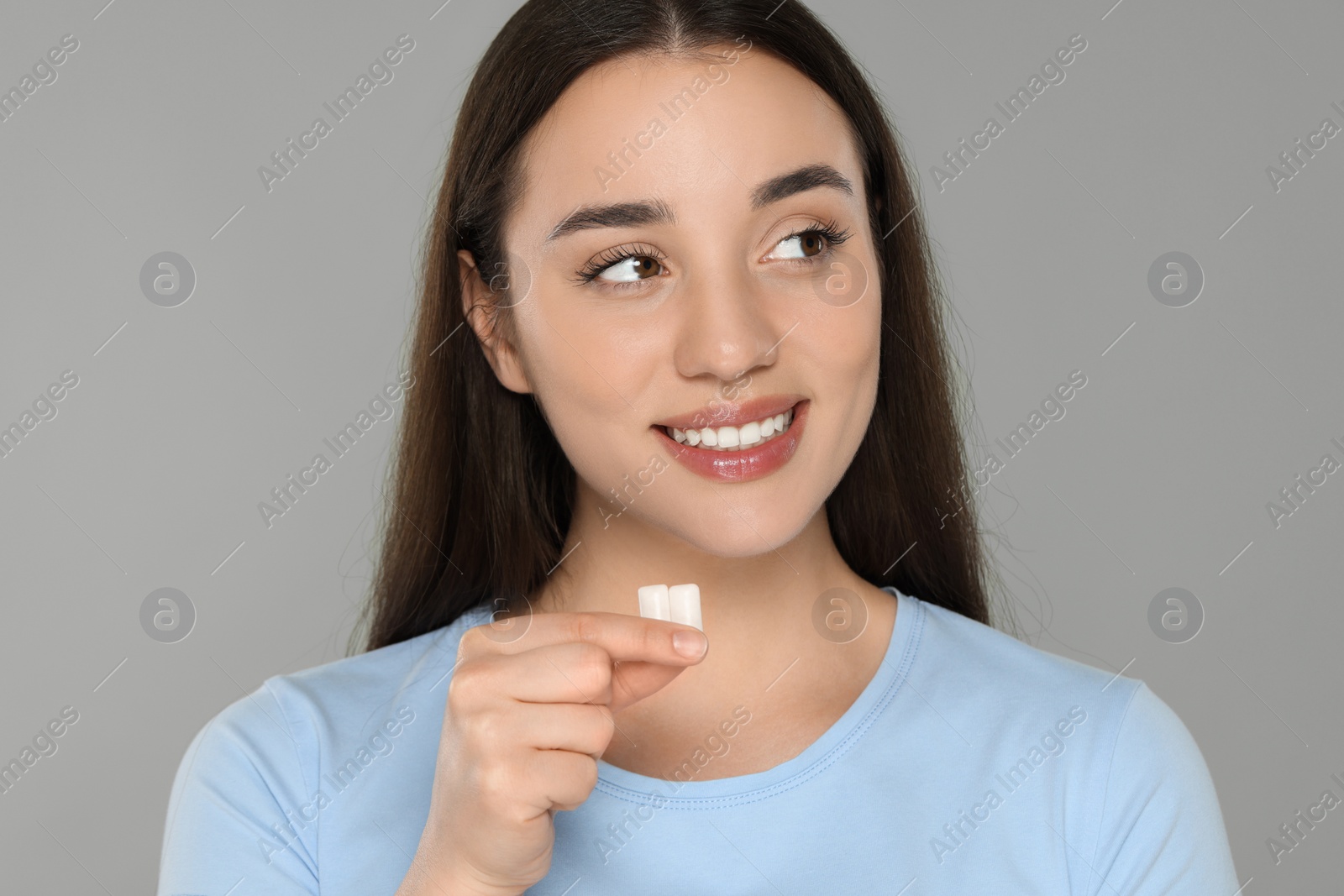 Photo of Happy young woman with bubble gums on grey background