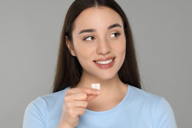 Happy young woman with bubble gums on grey background