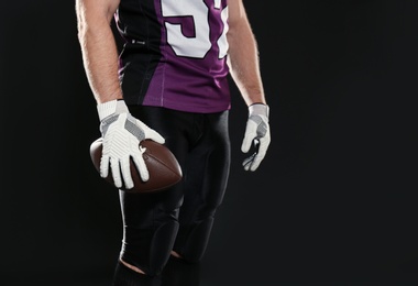 American football player with ball on dark background, closeup. Space for text