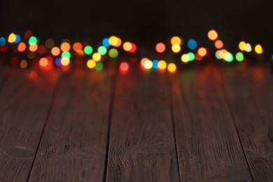 Colorful lights on wooden table, blurred view. Space for text