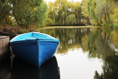 Photo of Light blue wooden boat on lake near pier, space for text