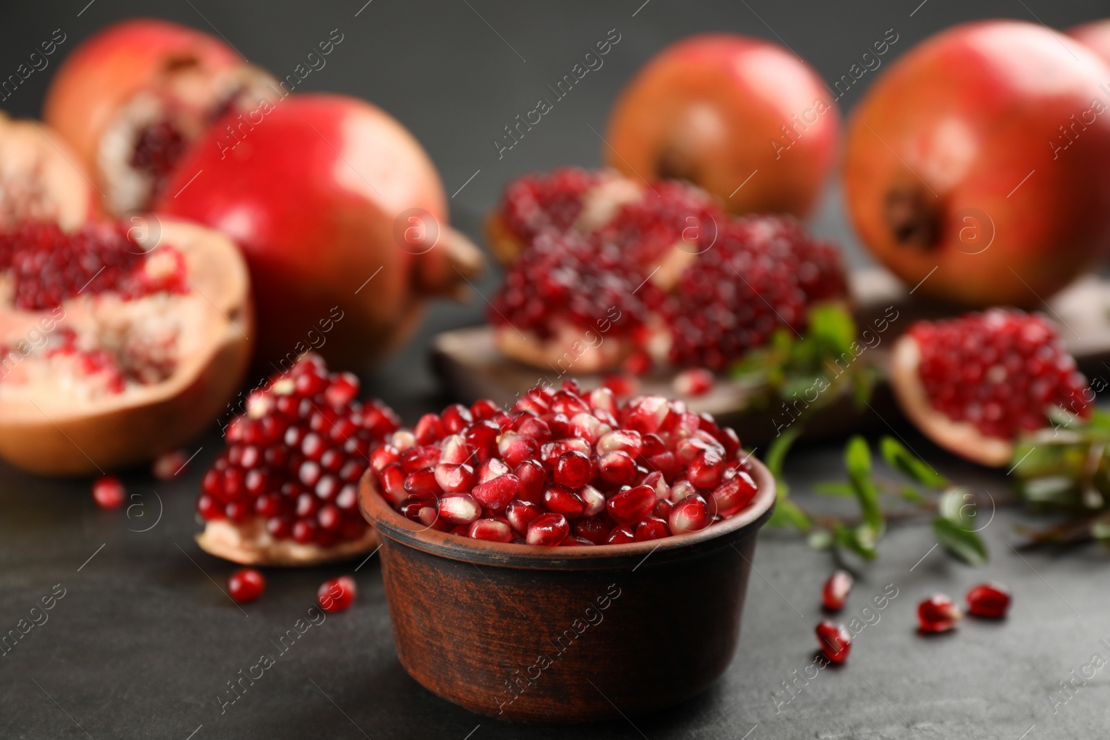 Photo of Delicious ripe pomegranate kernels in bowl on black table