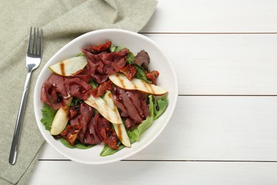 Delicious bresaola salad with sun-dried tomatoes, pear, balsamic vinegar and fork on white wooden table, flat lay. Space for text