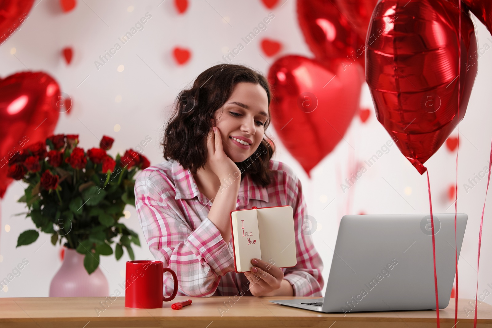 Photo of Valentine's day celebration in long distance relationship. Woman having video chat with her boyfriend via laptop indoors