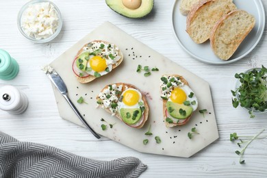 Photo of Delicious sandwiches with egg, cheese, avocado and microgreens on white wooden table, flat lay