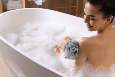 Photo of Woman taking bath with mesh pouf in tub