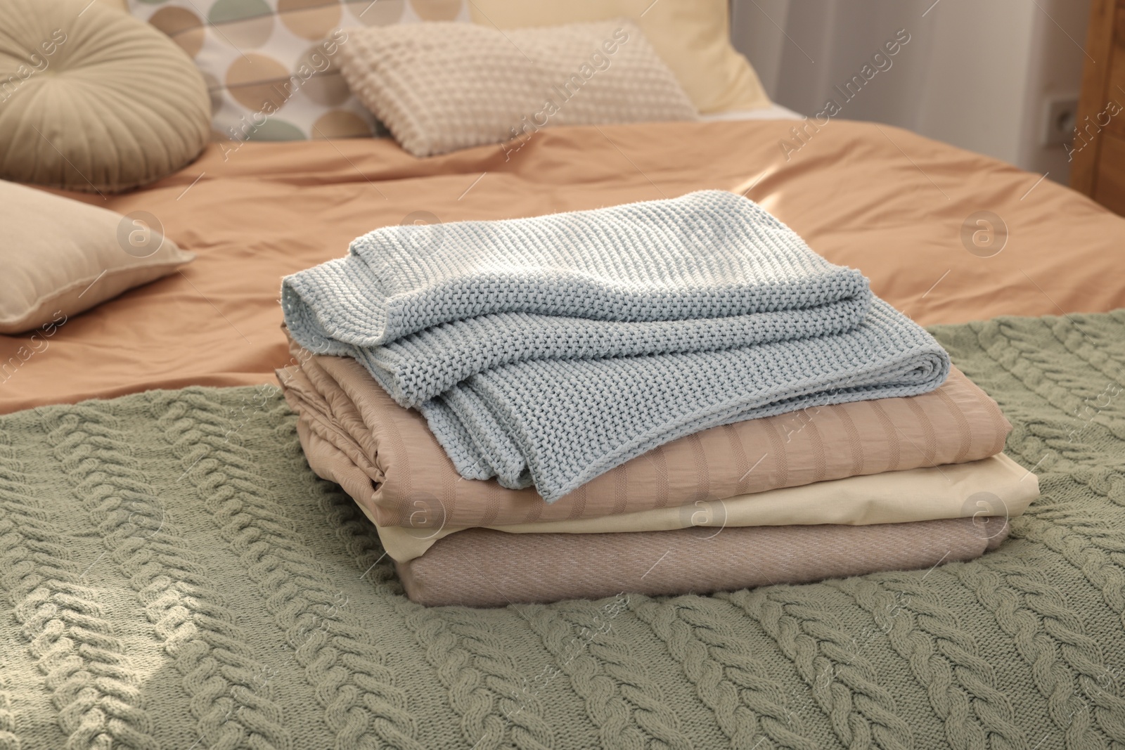 Photo of Stack of different folded blankets on bed indoors. Home textile