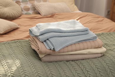 Stack of different folded blankets on bed indoors. Home textile