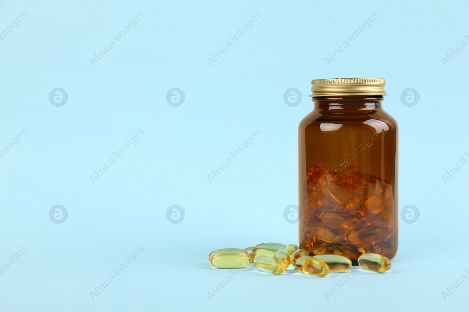 Photo of Jar with vitamin capsules on light blue background, space for text