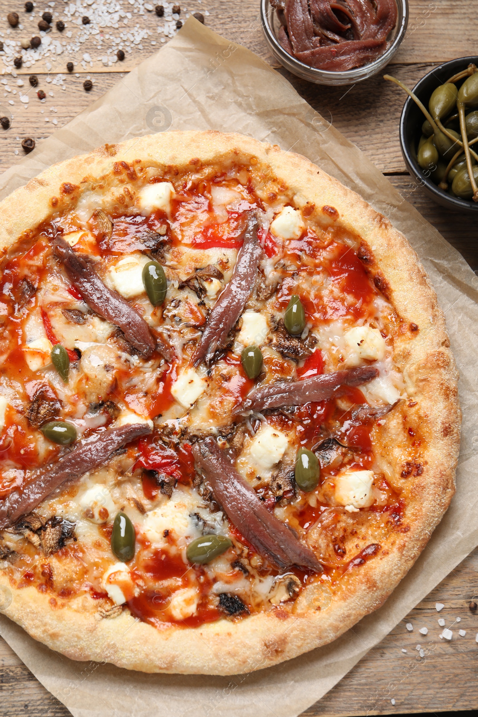 Photo of Tasty pizza with anchovies and ingredients on wooden table, flat lay