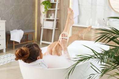 Woman with sponge taking bubble bath at home