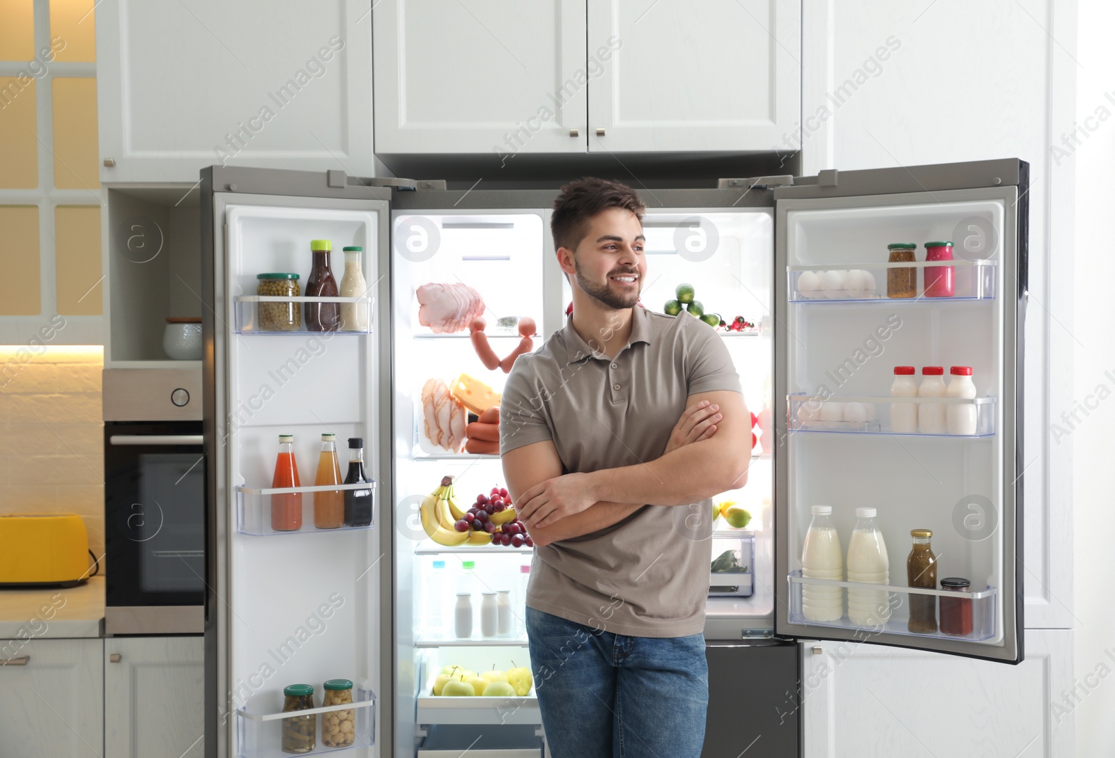 Photo of Young man near open refrigerator in kitchen