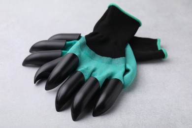 Photo of Pair of claw gardening gloves on light grey table, closeup