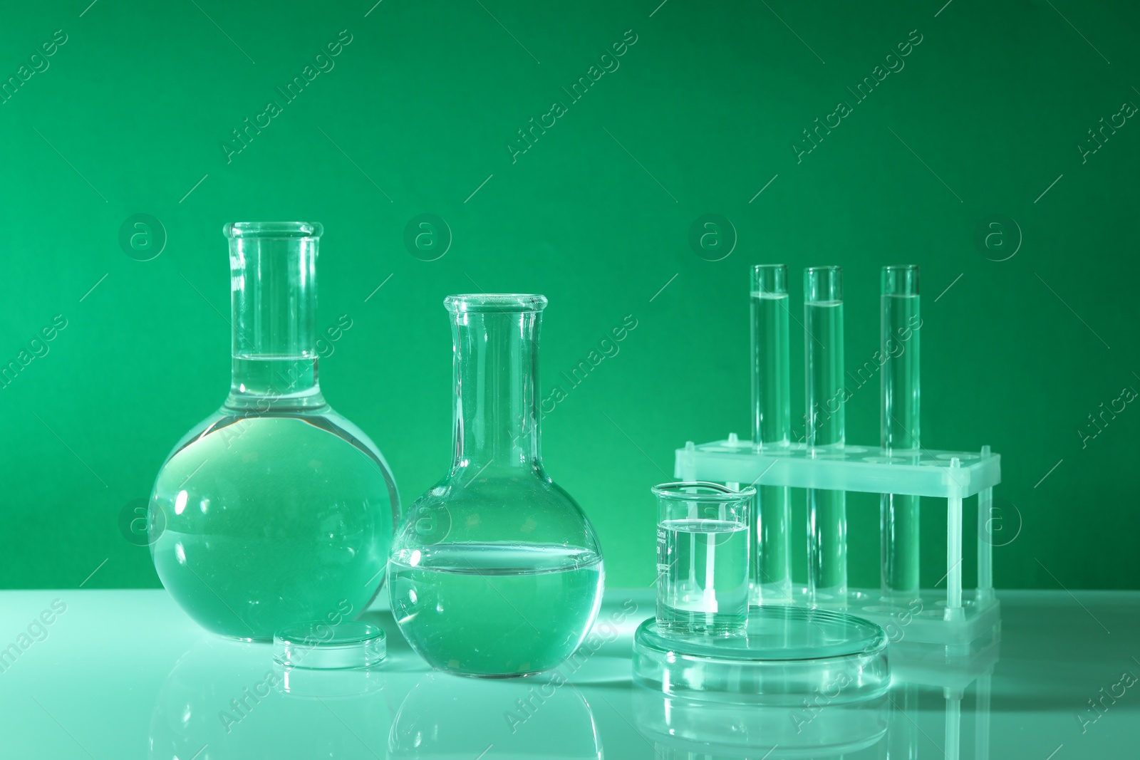 Photo of Laboratory analysis. Different glassware on table against green background