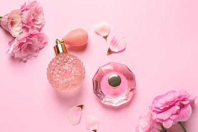 Photo of Flat lay composition with perfume bottles and flowers on light pink background