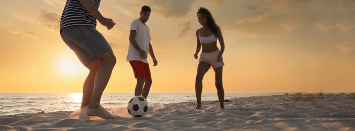 Image of Group of friends playing football on sandy beach, low angle view. Banner design