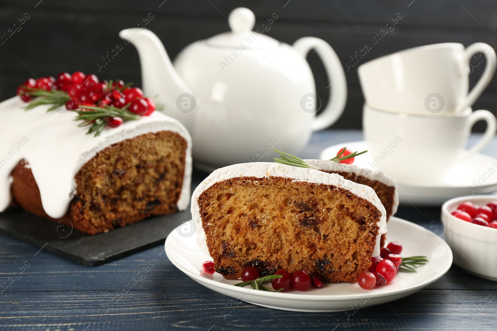 Photo of Traditional classic Christmas cake decorated with cranberries, pomegranate seeds and rosemary served on wooden table