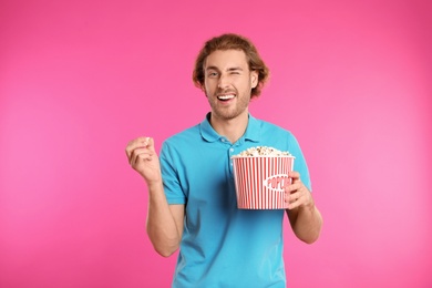 Man with popcorn during cinema show on color background